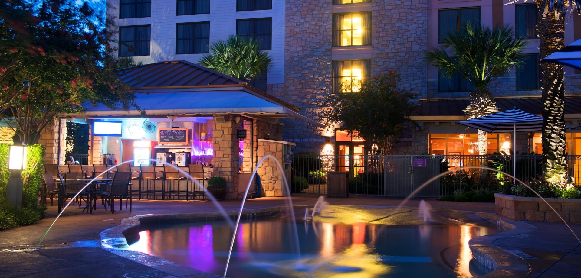 View of hotel pool with water shooting up for design in the dusk light.